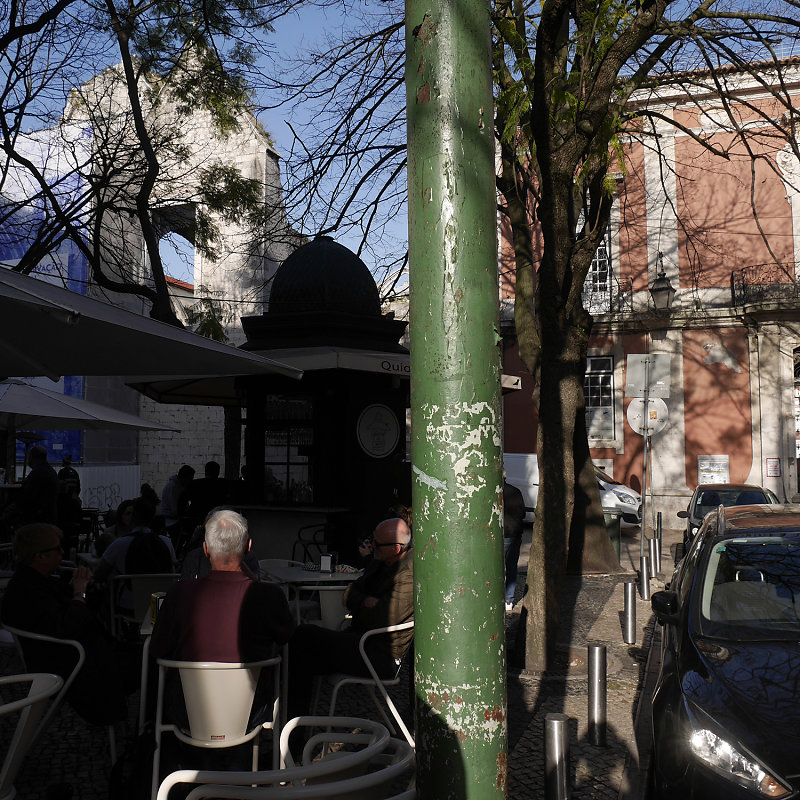 homme de dos assis à une terrasse, poteau vert, à Lisbonne, Portugal, 2018